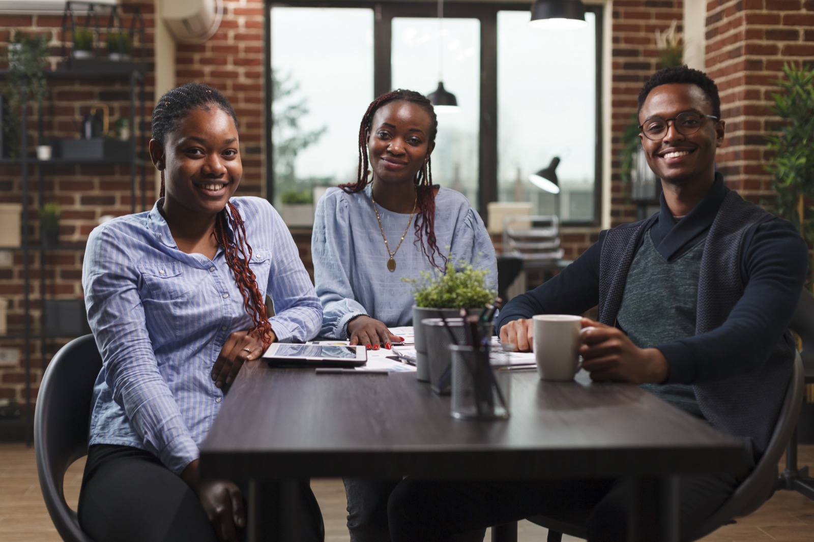 Three young African professionals in conversation around a table